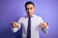 Young brazilian businessman wearing elegant tie standing over isolated purple background Pointing down looking sad and upset, Royalty Free Stock Photo