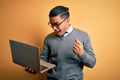 Young brazilian businessman working using laptop standing over isoltated yellow background screaming proud and celebrating victory Royalty Free Stock Photo