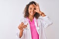 Young brazilian doctor woman holding glass of water standing over isolated white background with happy face smiling doing ok sign Royalty Free Stock Photo