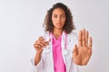 Young brazilian doctor woman holding glass of water standing over isolated white background with open hand doing stop sign with Royalty Free Stock Photo