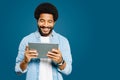 A young Brazilian man with an afro hairstyle is engrossed in his tablet, reading news or interacting with an application Royalty Free Stock Photo