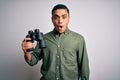 Young brazilian man looking through binoculars over isolated white background scared in shock with a surprise face, afraid and Royalty Free Stock Photo