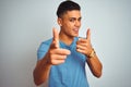 Young brazilian man wearing blue t-shirt standing over isolated white background pointing fingers to camera with happy and funny Royalty Free Stock Photo