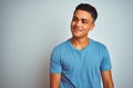 Young brazilian man wearing blue t-shirt standing over isolated white background smiling looking to the side and staring away Royalty Free Stock Photo