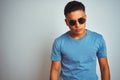 Young brazilian man wearing blue t-shirt and sunglasses over isolated white background with serious expression on face Royalty Free Stock Photo