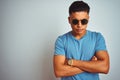 Young brazilian man wearing blue t-shirt and sunglasses over isolated white background skeptic and nervous, disapproving Royalty Free Stock Photo