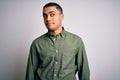 Young brazilian man wearing casual shirt standing over isolated white background smiling looking to the side and staring away Royalty Free Stock Photo