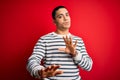 Young brazilian man wearing casual striped t-shirt standing over isolated red background Moving away hands palms showing refusal Royalty Free Stock Photo