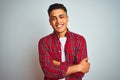 Young brazilian man wearing red shirt standing over isolated white background happy face smiling with crossed arms looking at the Royalty Free Stock Photo