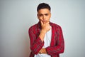 Young brazilian man wearing red shirt standing over isolated white background looking confident at the camera with smile with Royalty Free Stock Photo