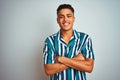 Young brazilian man wearing summer striped shirt standing over isolated white background happy face smiling with crossed arms Royalty Free Stock Photo