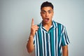 Young brazilian man wearing summer striped shirt standing over isolated white background pointing finger up with successful idea