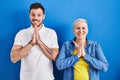 Young brazilian mother and son standing over blue background praying with hands together asking for forgiveness smiling confident Royalty Free Stock Photo