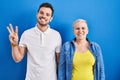 Young brazilian mother and son standing over blue background showing and pointing up with fingers number three while smiling