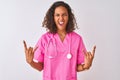 Young brazilian nurse woman wearing stethoscope standing over isolated white background shouting with crazy expression doing rock Royalty Free Stock Photo