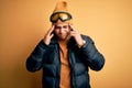 Young brazilian skier man wearing snow sportswear and ski goggles over yellow background with hand on headache because stress Royalty Free Stock Photo