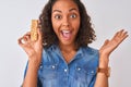 Young brazilian woman eating granola bar standing over isolated white background very happy and excited, winner expression Royalty Free Stock Photo