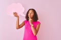 Young brazilian woman holding cloud speech bubble standing over isolated pink background serious face thinking about question,