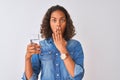 Young brazilian woman holding glass of water standing over isolated white background cover mouth with hand shocked with shame for Royalty Free Stock Photo