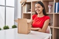 Young brazilian woman looking inside cardboard box happy face smiling with crossed arms looking at the camera Royalty Free Stock Photo