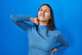 Young brazilian woman standing over blue isolated background suffering of neck ache injury, touching neck with hand, muscular pain Royalty Free Stock Photo