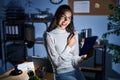 Young brazilian woman using touchpad at night working at the office with a big smile on face, pointing with hand finger to the Royalty Free Stock Photo