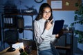 Young brazilian woman using touchpad at night working at the office cheerful with a smile on face pointing with hand and finger up Royalty Free Stock Photo