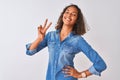 Young brazilian woman wearing denim shirt standing over isolated white background smiling looking to the camera showing fingers Royalty Free Stock Photo