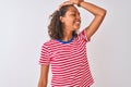 Young brazilian woman wearing red striped t-shirt standing over isolated white background smiling confident touching hair with Royalty Free Stock Photo