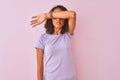Young brazilian woman wearing t-shirt standing over isolated pink background covering eyes with arm, looking serious and sad Royalty Free Stock Photo