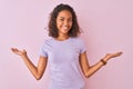 Young brazilian woman wearing t-shirt standing over isolated pink background smiling showing both hands open palms, presenting and