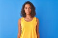 Young brazilian woman wearing yellow t-shirt standing over isolated blue background Relaxed with serious expression on face Royalty Free Stock Photo