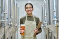 Young brewer tasting beer in brewery