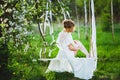 Young bride with blond hair in white negligee and stockings putting on a garter