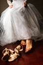 A young bride is going to put on her shoes. She is wearing a wedding dress Royalty Free Stock Photo