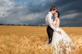 Young bride and groom posing in wheat field with dramatic sky in Royalty Free Stock Photo