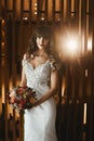 Young bride in luxurious wedding dress looking at the camera and posing at the dark interior. Young model woman with Royalty Free Stock Photo