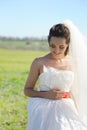 Young bride outdoor portrait in white dress against green field Royalty Free Stock Photo