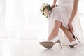 Young bride putting on beautiful wedding shoes indoors closeup. Space for text