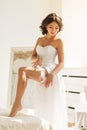 Young bride putting garter on her leg Royalty Free Stock Photo