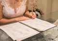 Young bride`s hands put signature on consent to marriage close-up Royalty Free Stock Photo