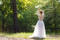 A young bride stands in the park with her back. Pretty unusually posing on camera Royalty Free Stock Photo