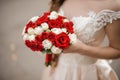 Young bride in a wedding dress holding a bouquet of white and red roses Royalty Free Stock Photo
