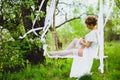 Young bride with blond hair in white negligee and stockings putting on a garter