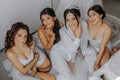 Young bridesmaids in white silk dresses on a bed in the bride's room Royalty Free Stock Photo