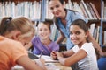 Young bright minds. A young girl sitting in the library working with her classmates.