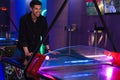 Young bristle man laughing while playing air hockey