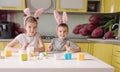 A young brother and sister with rabbit ears on their head paints Easter eggs at home in the kitchen. preparing for the Easter Royalty Free Stock Photo