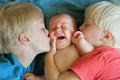 Young Brothers Kissing their Crying Newborn Baby Sister Royalty Free Stock Photo