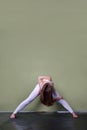 Young brown-haired girl in oigi pose - Parivrata prasarita padottanasana - Bend with legs wide apart with twisting.